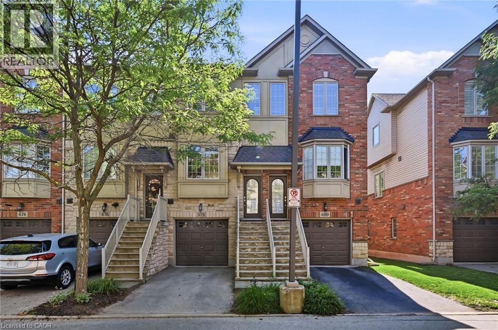 Brick and stone facade townhome featuring a private entrance, covered porch, and integrated garage - 678 Rowley Common, Burlington, ON - Outdoor With Facade