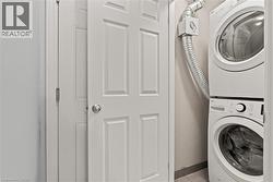 Laundry area featuring baseboards and stacked washing machine and dryer - 