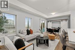 Living room with a barn door, wood finished floors, and a tray ceiling - 