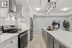 Kitchen featuring stainless steel appliances, two tone cabinets, light stone countertops, tasteful backsplash, and hanging light fixtures - 