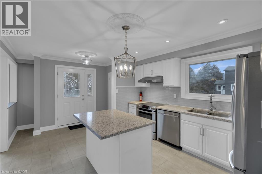 Contemporary kitchen featuring white cabinetry, stainless steel appliances, a light-toned stone countertop island, and a subway tile backsplash - 197 Troy Street, Mississauga, ON - Indoor Photo Showing Kitchen With Double Sink With Upgraded Kitchen
