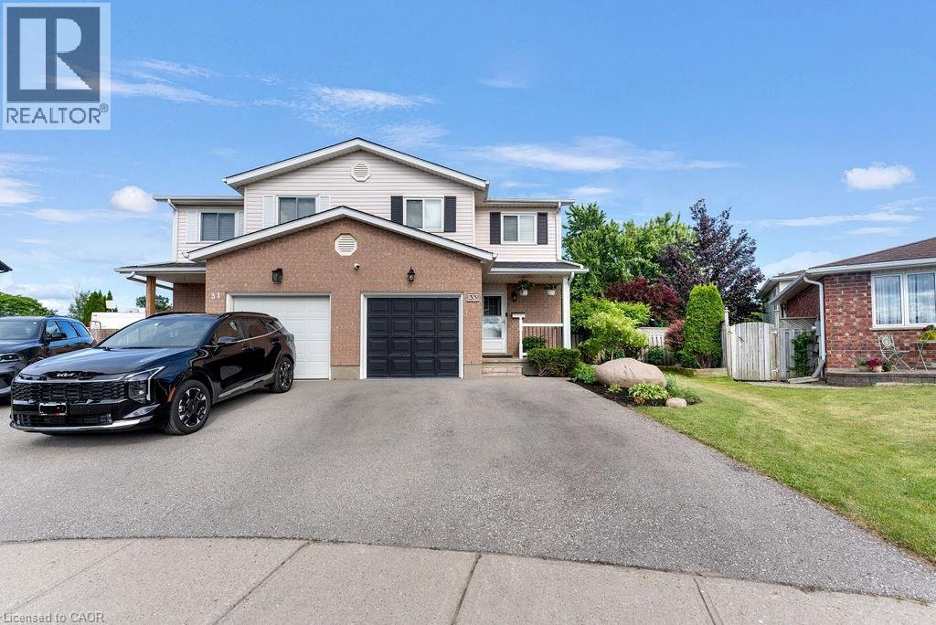 Two-story residence featuring brick and siding exterior, a two-car garage with both panel and carriage-style doors, and a paved driveway - 33 Remple Court, Cambridge, ON - Outdoor With Facade