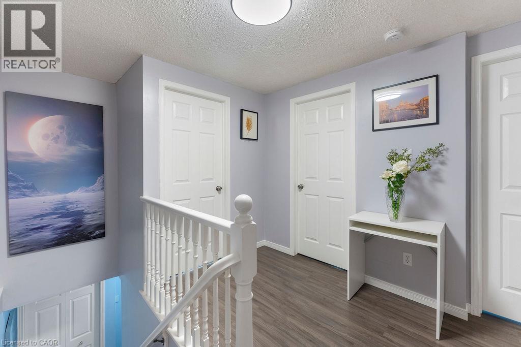 Upper-level landing featuring wood-finish flooring, light gray walls, white paneled doors, and a white balustrade - 33 Remple Court, Cambridge, ON - Indoor Photo Showing Other Room