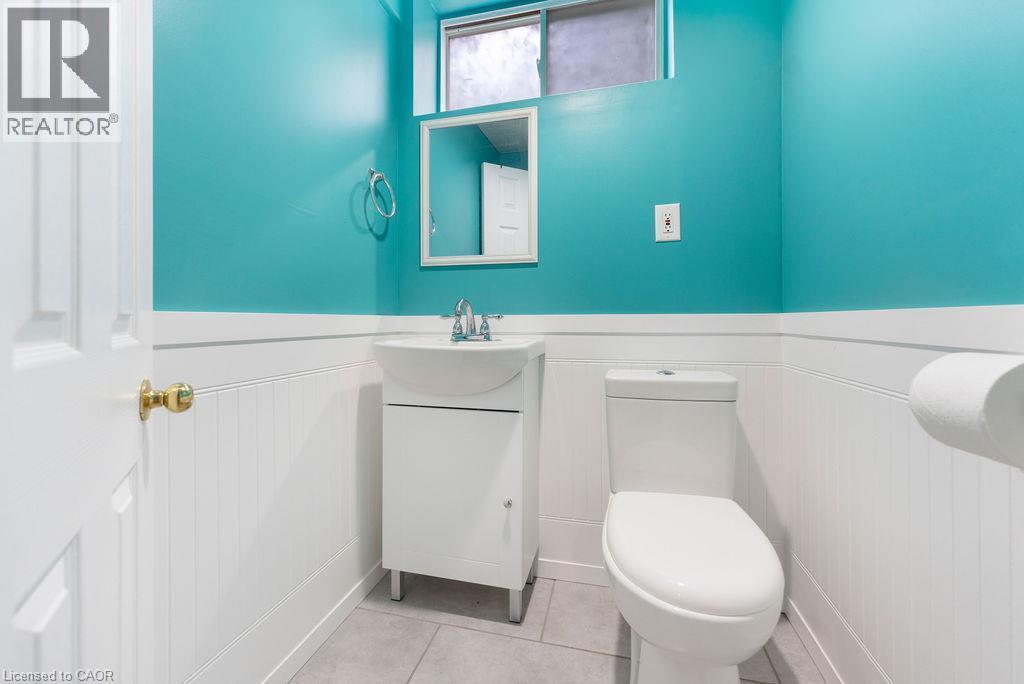 Powder room featuring a pedestal sink with chrome faucet, white beadboard wainscoting, and large format tile flooring - 33 Remple Court, Cambridge, ON - Indoor Photo Showing Bathroom