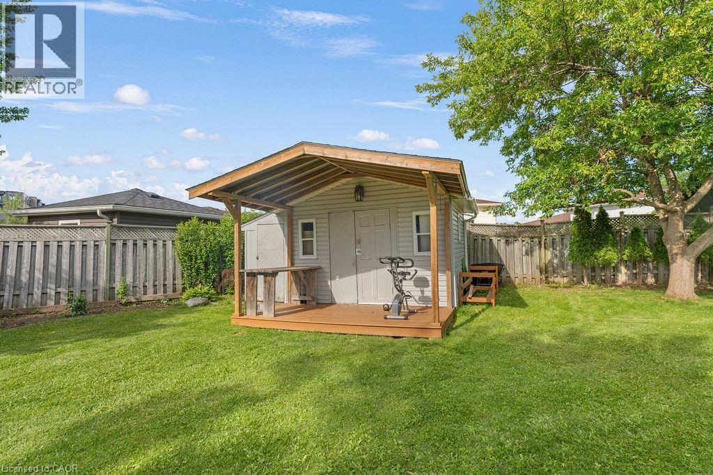 Expansive backyard featuring a central shed with a covered wood-finish deck and additional storage - 33 Remple Court, Cambridge, ON - Outdoor With Deck Patio Veranda