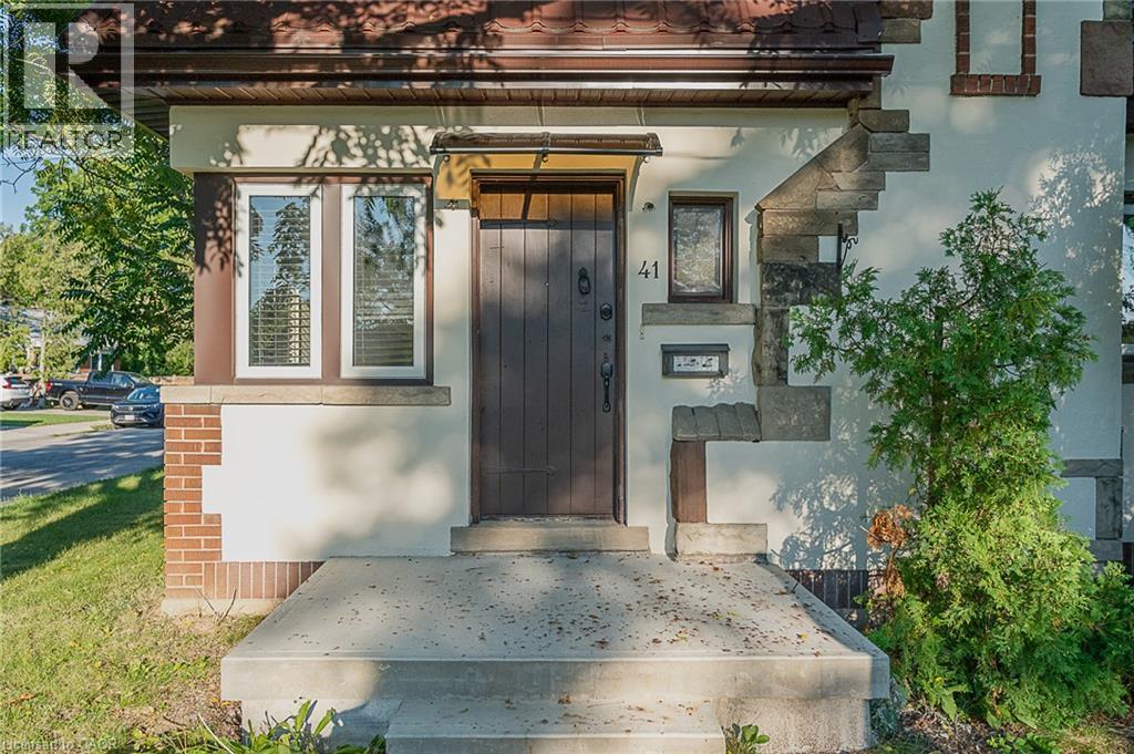 Stone and stucco facade with a dark wood-finish entry door, concrete steps, and a decorative awning - 41 Paradise Road S, Hamilton, ON - Outdoor