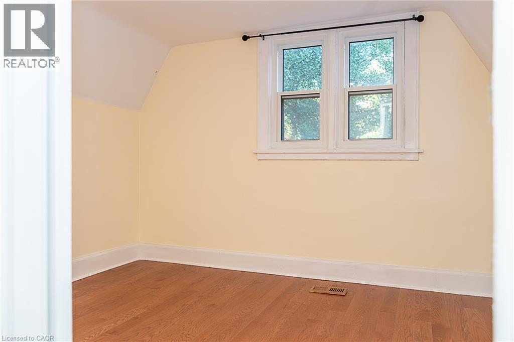 Hardwood-finish flooring, white window trim, and sloped ceiling - 41 Paradise Road S, Hamilton, ON - Indoor Photo Showing Other Room