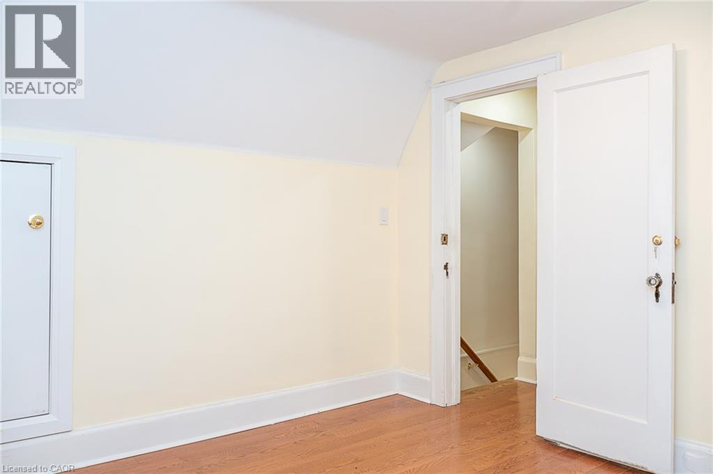 Hardwood flooring, painted walls, white trim, attic access panel, and a paneled interior door - 41 Paradise Road S, Hamilton, ON - Indoor Photo Showing Other Room