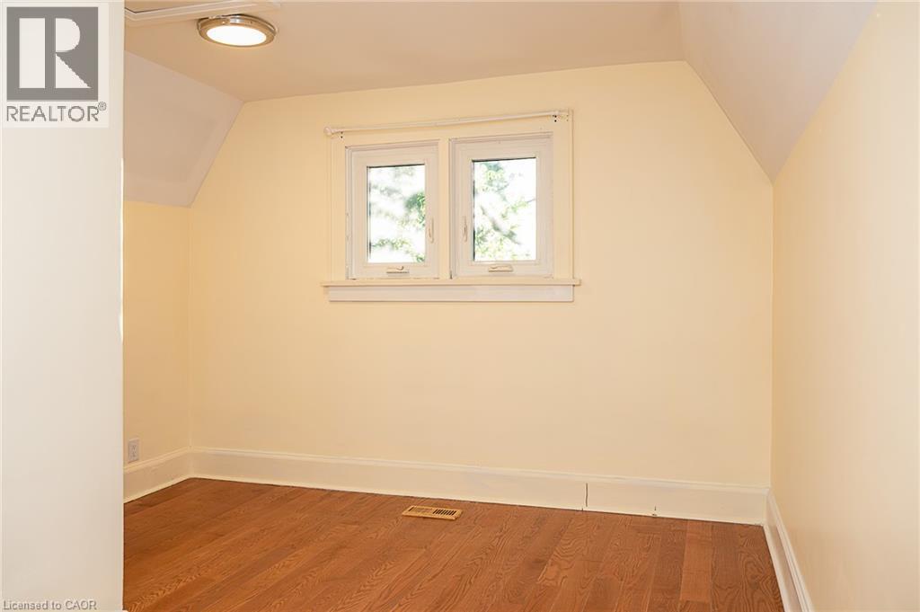 Hardwood flooring, painted walls, window with trim, flush mount ceiling light, and sloped ceiling details - 41 Paradise Road S, Hamilton, ON - Indoor Photo Showing Other Room