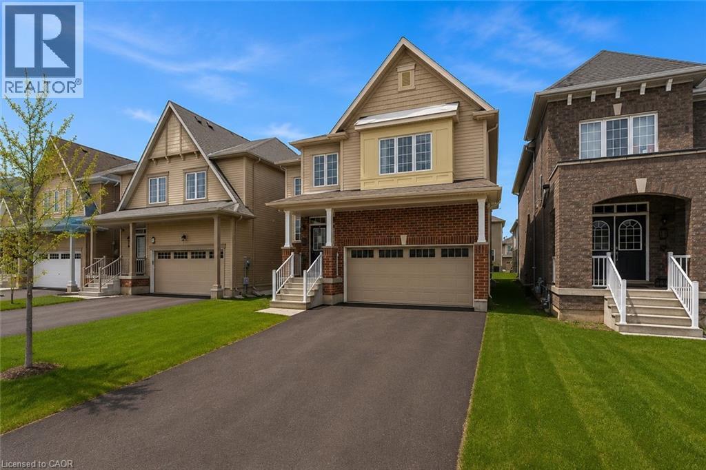 Two-story residence featuring a brick and siding exterior, covered front porch, an attached garage, paved driveway, and manicured front lawn - 13 Steven Drive, Thorold, ON - Outdoor With Facade