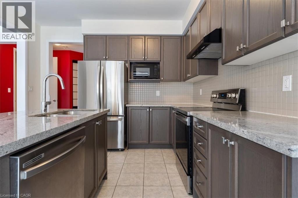 Kitchen featuring light tile patterned floors, under cabinet range hood, stainless steel appliances, a sink, and decorative backsplash - 13 Steven Drive, Thorold, ON - Indoor Photo Showing Kitchen With Double Sink With Upgraded Kitchen