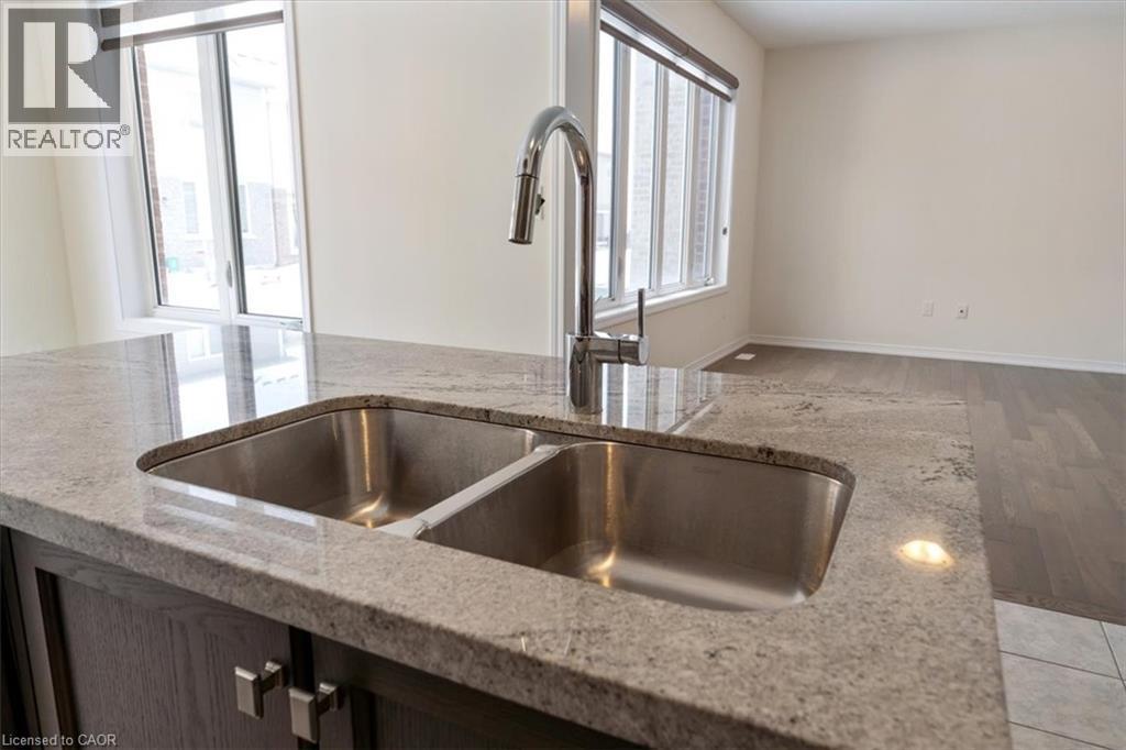 Details with light wood-type flooring, baseboards, light stone counters, and a sink - 13 Steven Drive, Thorold, ON - Indoor Photo Showing Kitchen With Double Sink