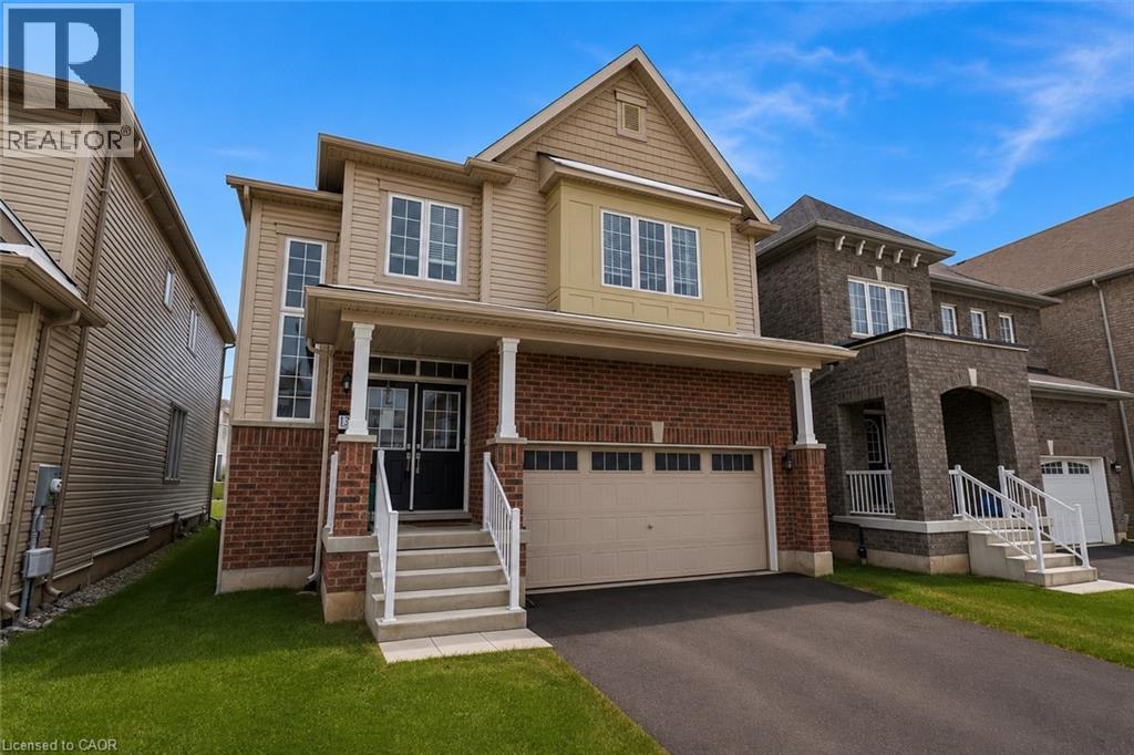 Brick and siding exterior with a covered porch, white columns, and a two-car garage - 13 Steven Drive, Thorold, ON - Outdoor With Facade