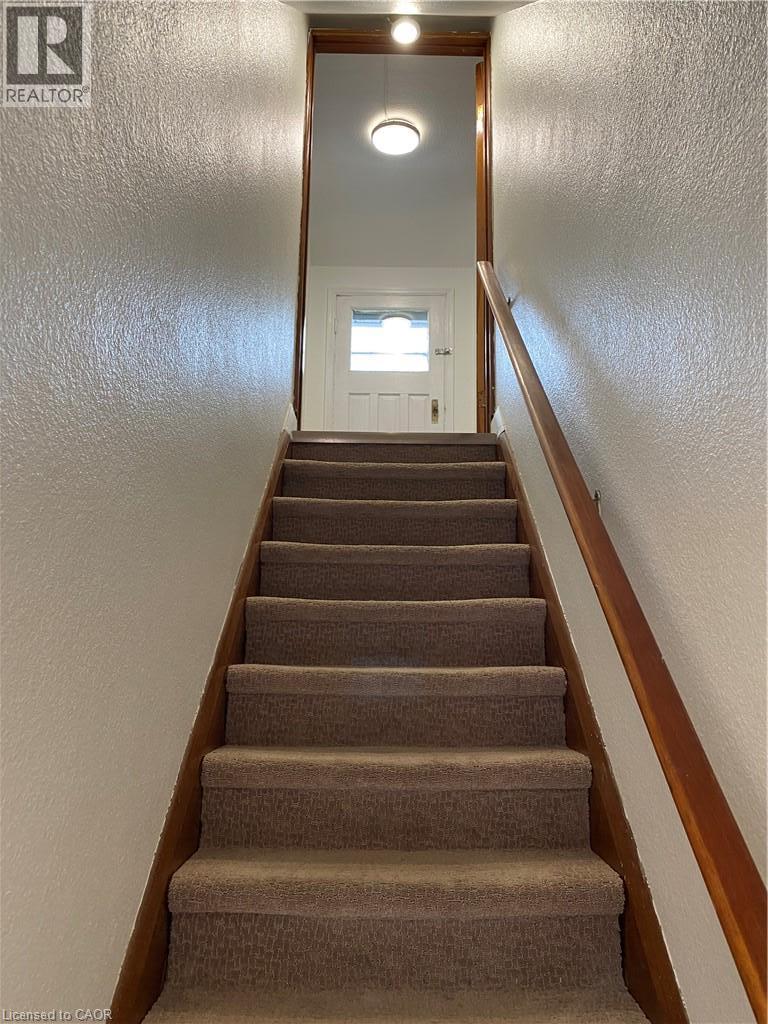 Carpeted staircase with wood-finish handrail and trim - 49 West Avenue, Kitchener, ON - Indoor Photo Showing Other Room