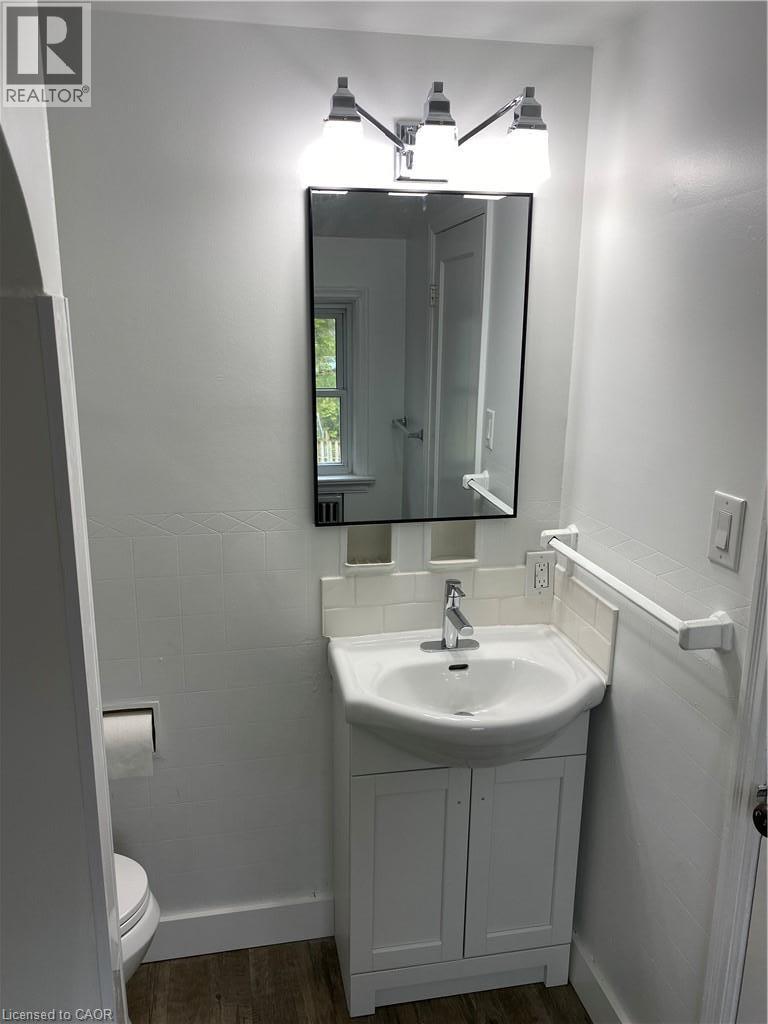 Vanity with integrated sink, chrome faucet, white subway tile backsplash, framed mirror, and chrome-finish lighting fixture - 49 West Avenue, Kitchener, ON - Indoor Photo Showing Bathroom