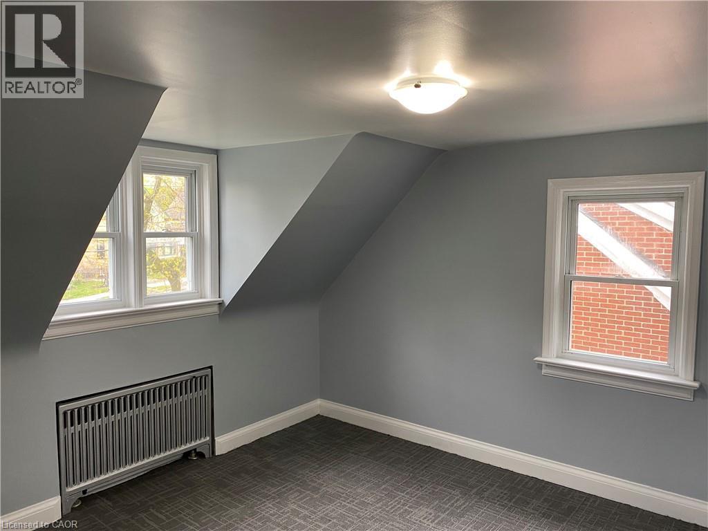 Room featuring two double-hung windows, sloped ceilings, a flush mount ceiling light fixture, and wall-to-wall carpeting - 49 West Avenue, Kitchener, ON - Indoor Photo Showing Other Room