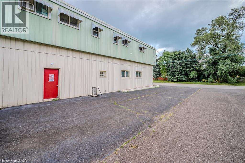 Commercial or industrial building featuring a two-tone metal exterior with upper green corrugated panels and lower cream-colored siding - 459 Enfield Road, Burlington, ON