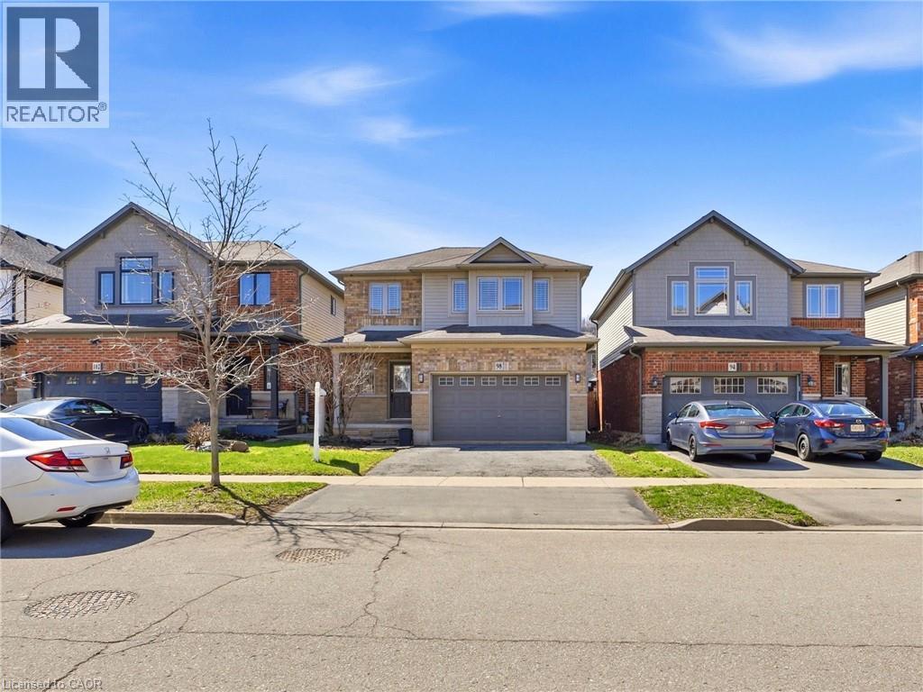 Two-story residence featuring a brick and siding exterior, an attached two-car garage, an asphalt driveway, a covered front entry, and a manicured front lawn - 98 Willow Lane, Grimsby, ON - Outdoor With Facade