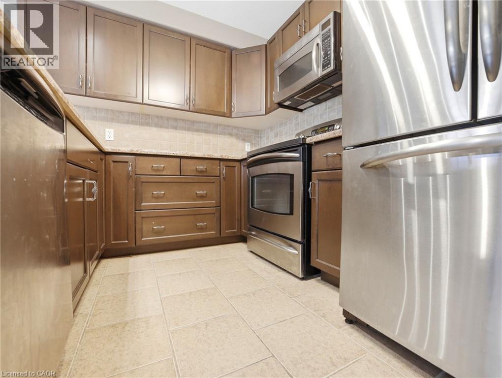 Kitchen featuring a full suite of stainless steel appliances, light-toned cabinetry, a complementary tile backsplash, and durable floor tiling - 98 Willow Lane, Grimsby, ON - Indoor Photo Showing Kitchen