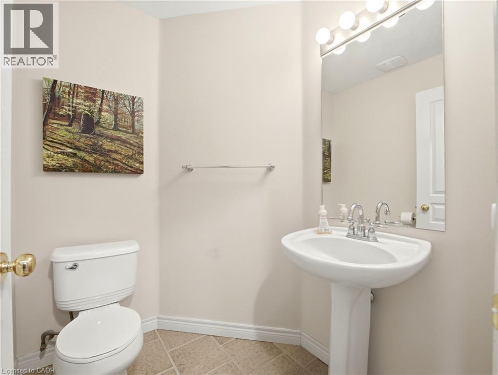 Pedestal sink with chrome faucet, large vanity mirror, and globe light fixture - 98 Willow Lane, Grimsby, ON - Indoor Photo Showing Bathroom