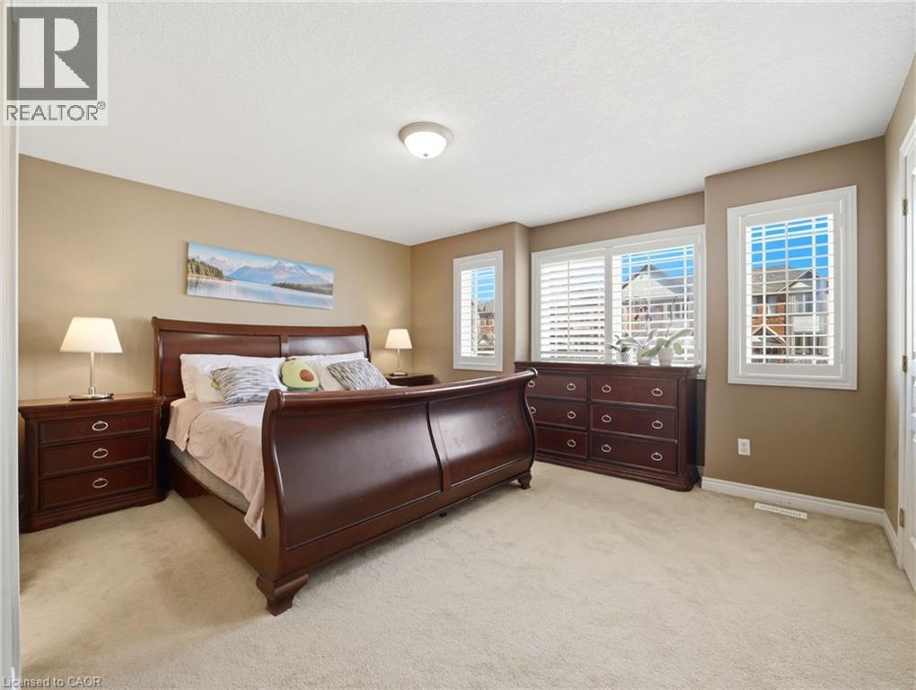 Carpeted room featuring multiple windows with white plantation shutters, neutral-toned walls, and a ceiling-mounted light fixture - 98 Willow Lane, Grimsby, ON - Indoor Photo Showing Bedroom
