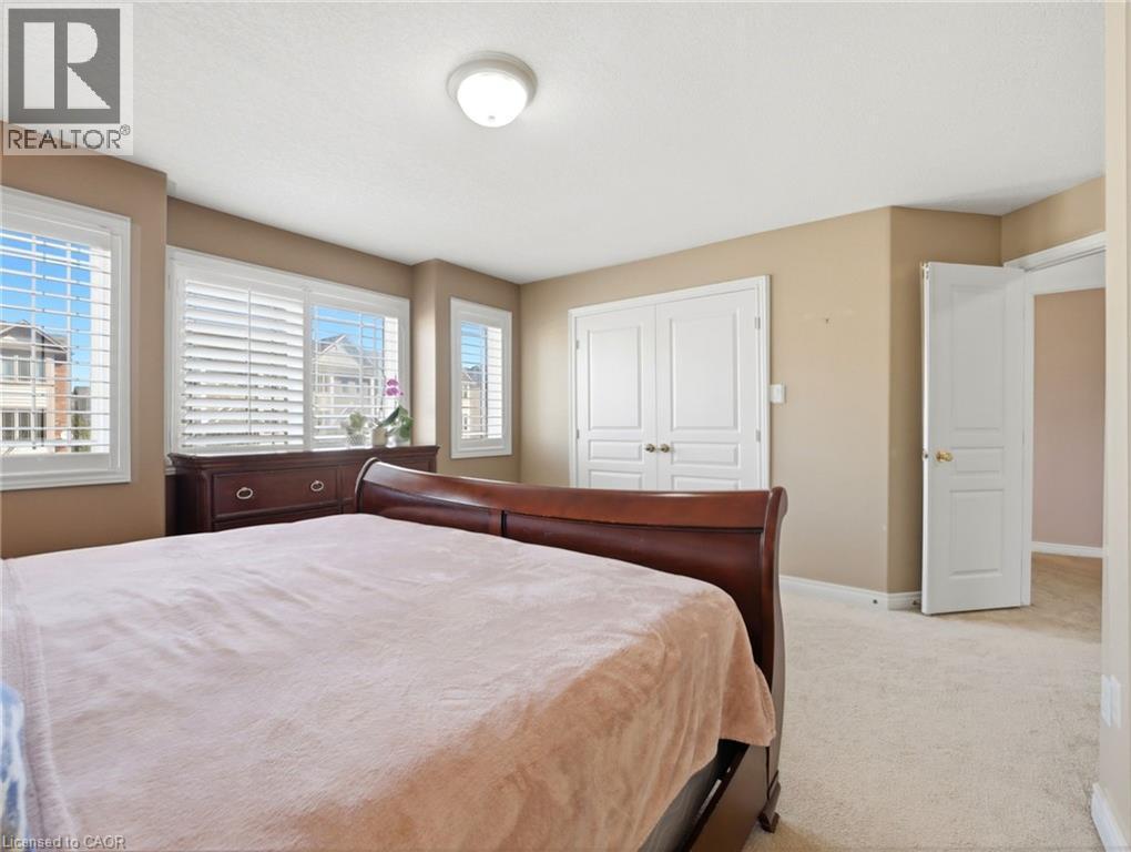 Carpeted room featuring multiple windows with white plantation shutters, a white ceiling, and a white flush-mount light fixture - 98 Willow Lane, Grimsby, ON - Indoor Photo Showing Bedroom