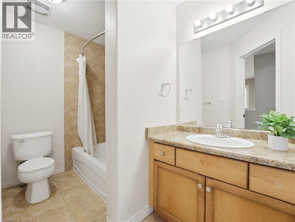 Full bathroom featuring a single vanity with a laminate countertop, light wood-finish cabinetry, and a full-width mirror - 98 Willow Lane, Grimsby, ON - Indoor Photo Showing Bathroom