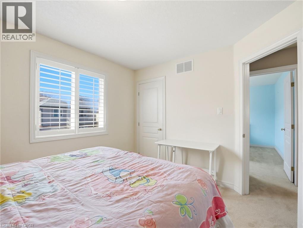 Interior room featuring a window with white louvered shutters, light beige wall paint, and carpeted flooring - 98 Willow Lane, Grimsby, ON - Indoor Photo Showing Bedroom