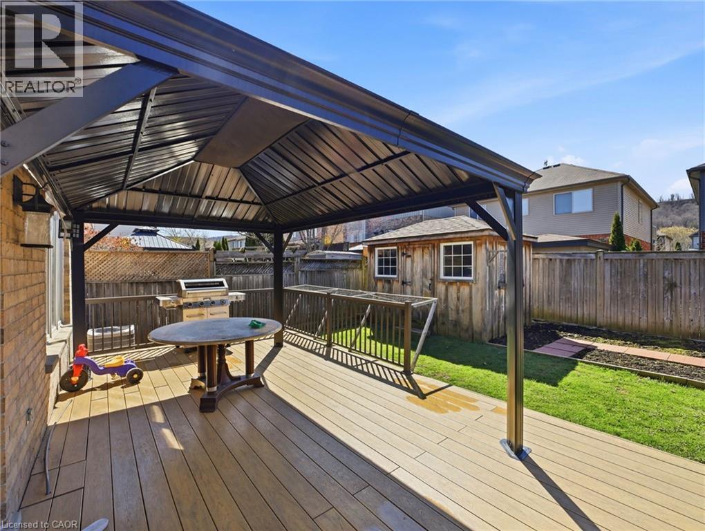 Expansive rear deck featuring wood-finish composite decking under a dark metal gazebo - 98 Willow Lane, Grimsby, ON - Outdoor With Deck Patio Veranda With Exterior