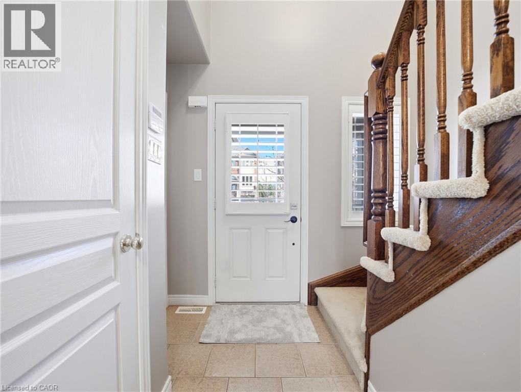 Front entry featuring neutral tile flooring, a white door with louvered glass, and a natural wood staircase with carpeted treads - 98 Willow Lane, Grimsby, ON - Indoor Photo Showing Other Room