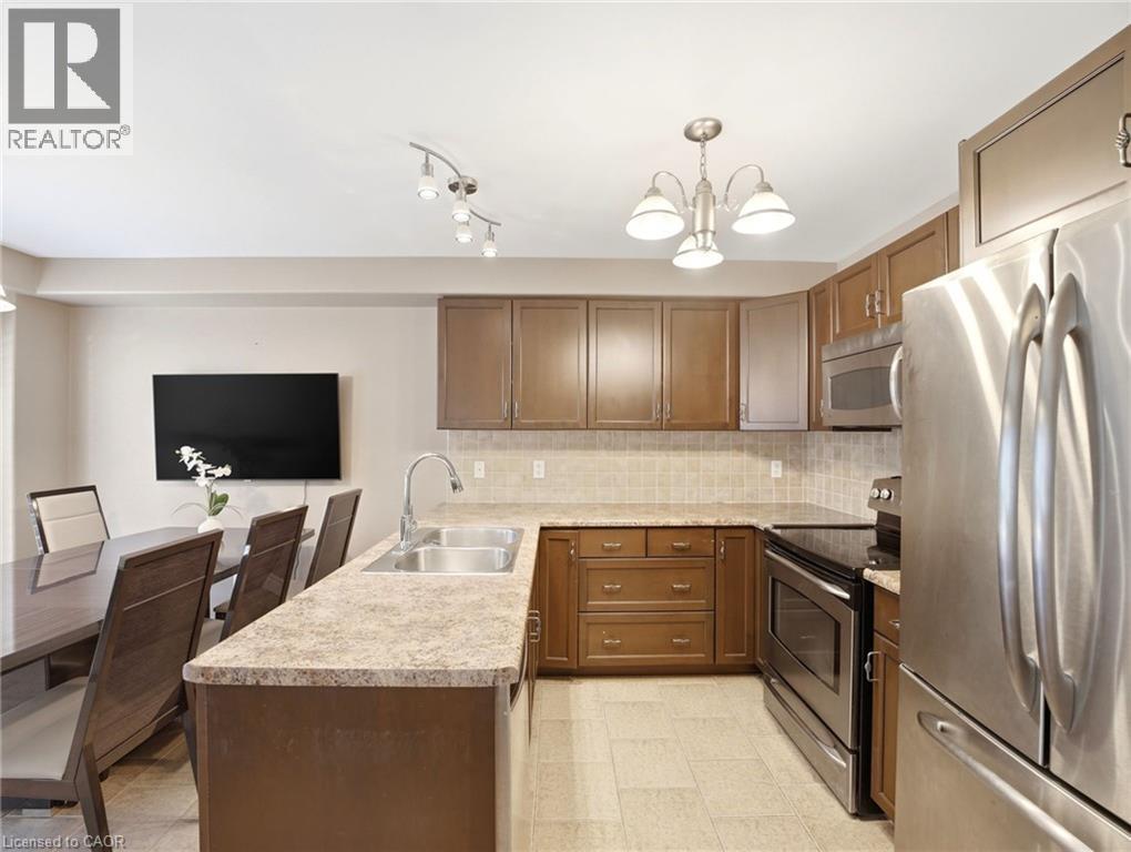 Kitchen featuring wood cabinetry, stainless steel appliances, a double basin sink, and a tile backsplash - 98 Willow Lane, Grimsby, ON - Indoor Photo Showing Kitchen With Stainless Steel Kitchen With Double Sink