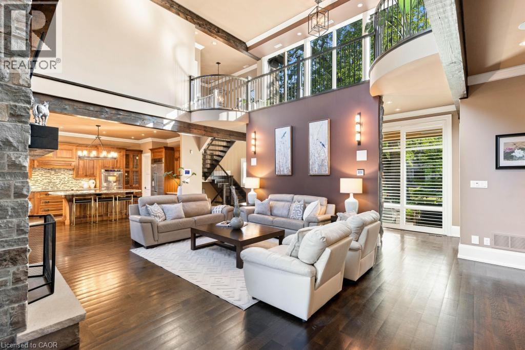 Spacious living area featuring high ceilings, exposed architectural beams, dark wood-finish flooring, and a stone-clad fireplace - 253 Rossmore Boulevard, Burlington, ON - Indoor Photo Showing Living Room