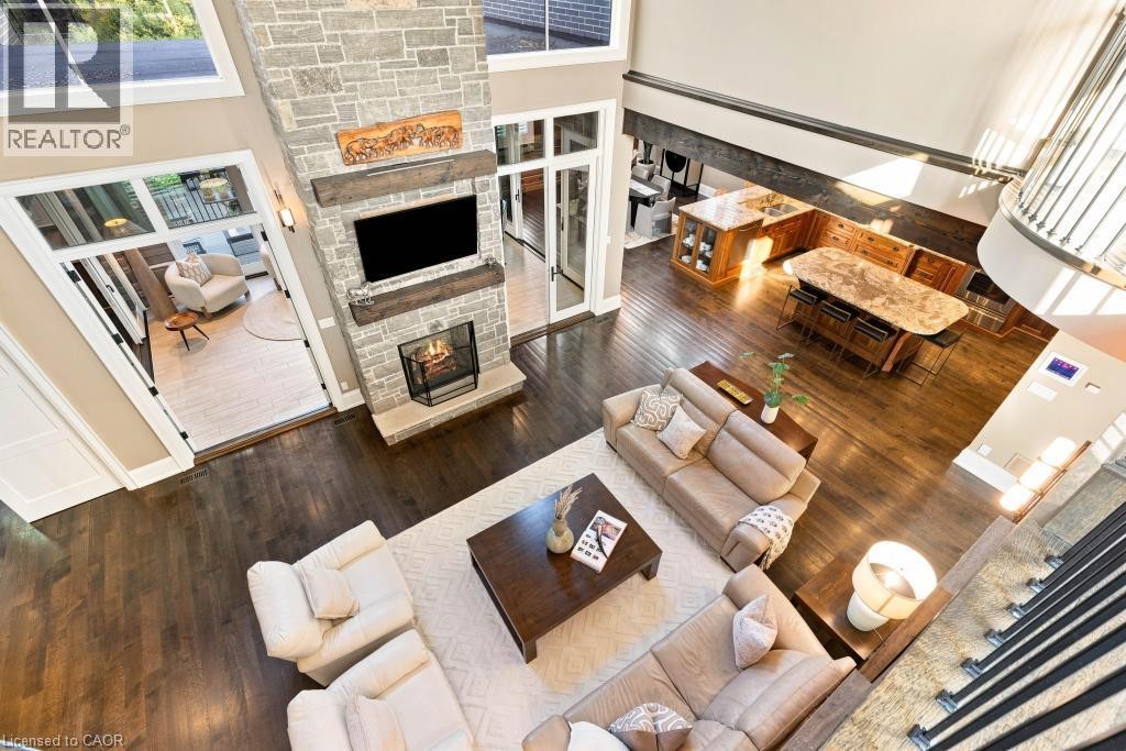 Soaring ceilings and dark wood-finish flooring define this open-concept living space - 253 Rossmore Boulevard, Burlington, ON - Indoor Photo Showing Living Room With Fireplace