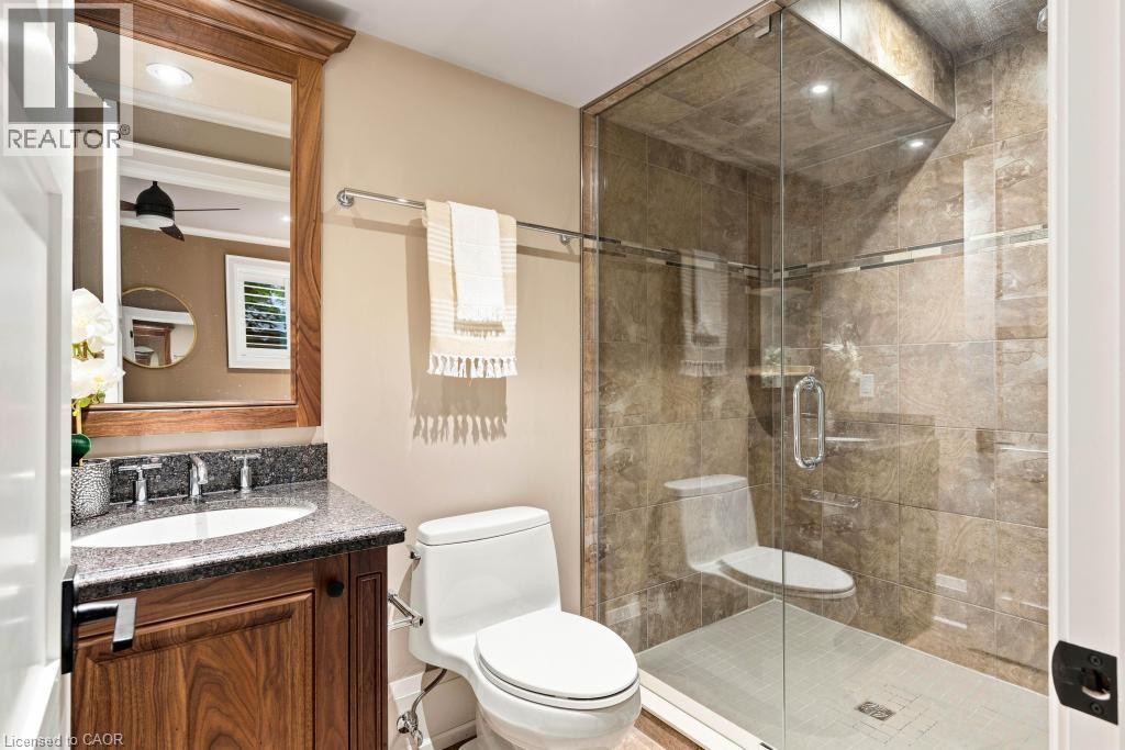 Wood-finish vanity with a dark speckled countertop, recessed sink, and chrome-finish faucet - 253 Rossmore Boulevard, Burlington, ON - Indoor Photo Showing Bathroom
