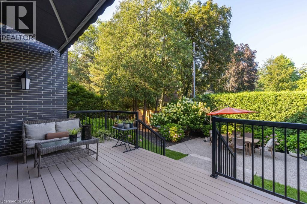 Composite deck with black metal railings, leading to a lower patio area featuring gravel and pavers - 253 Rossmore Boulevard, Burlington, ON - Outdoor With Deck Patio Veranda With Exterior