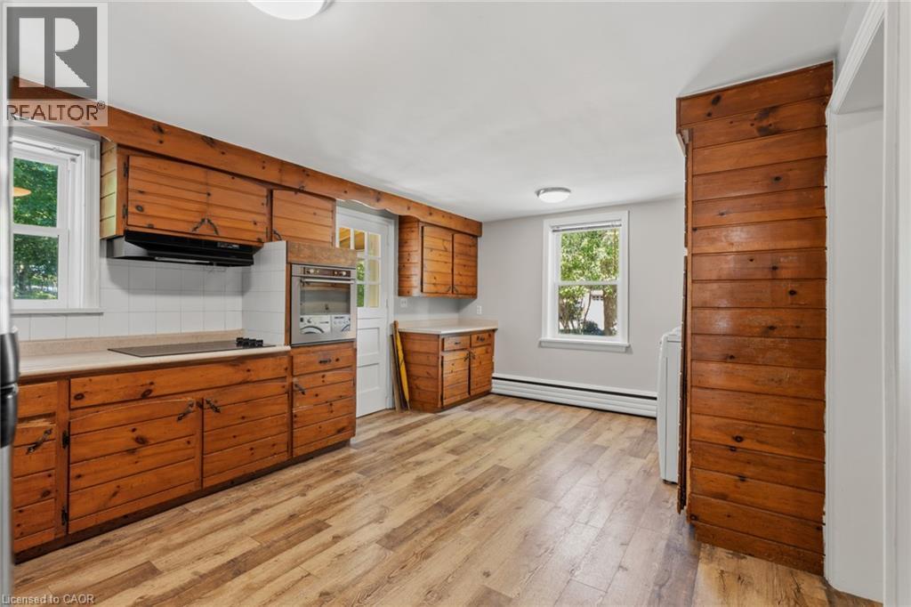 Kitchen featuring extensive wood cabinetry, wood-finish flooring, white tiled backsplash, built-in oven, and natural light from multiple windows - 41 Mill Street, Mississauga, ON - Indoor Photo Showing Kitchen