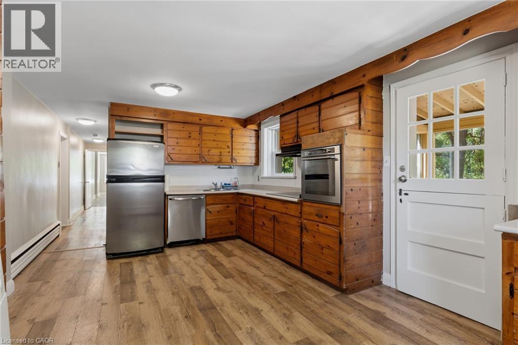 Kitchen featuring wood-paneled walls, wood-finish flooring, stainless steel appliances, and a Dutch door with glass panes - 41 Mill Street, Mississauga, ON - Indoor Photo Showing Kitchen