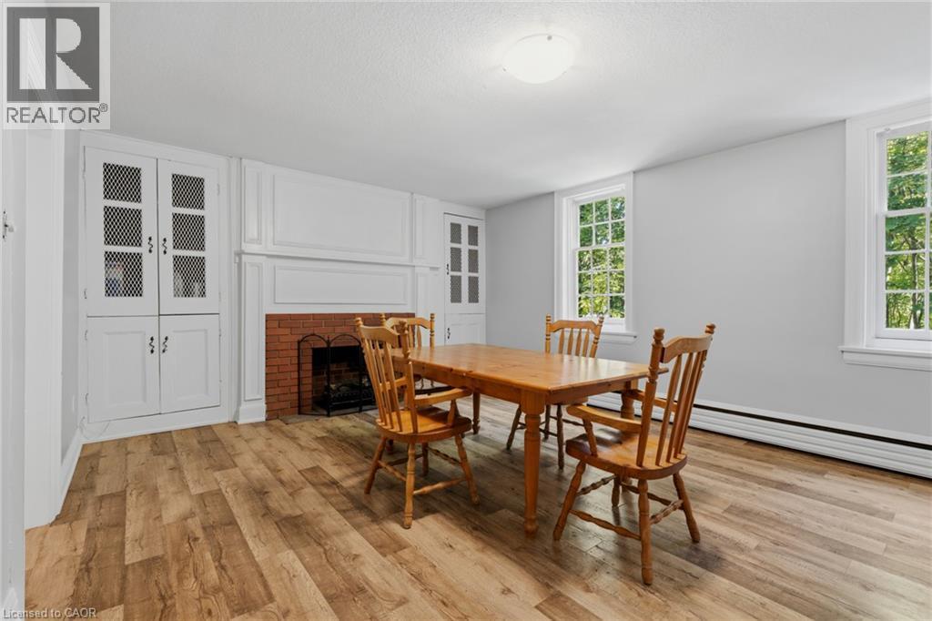 Spacious room featuring wood-finish flooring, a brick fireplace with a white mantel, built-in cabinetry with decorative grilles, and two large windows providing natural light - 41 Mill Street, Mississauga, ON - Indoor Photo Showing Dining Room