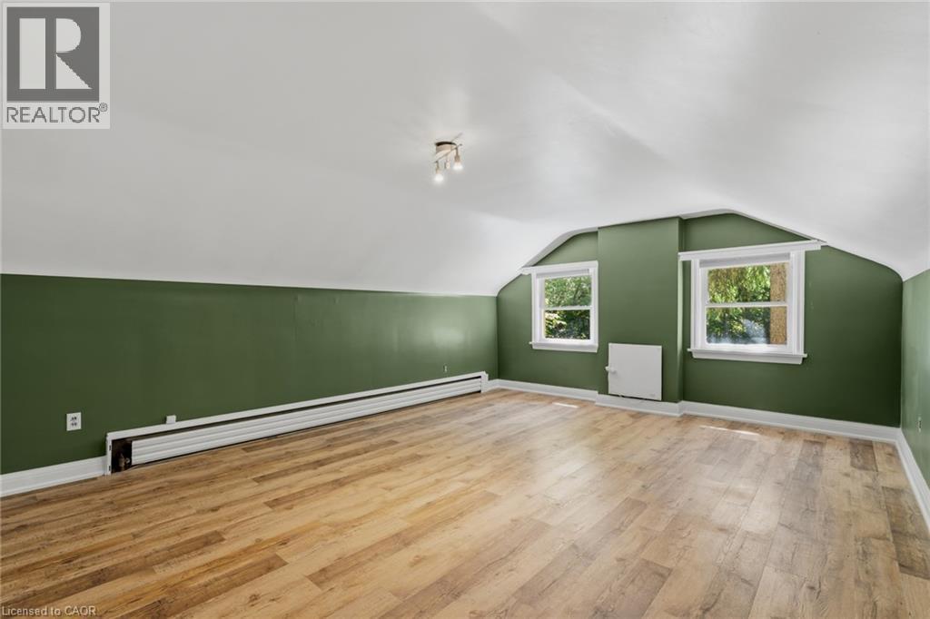 Bright room featuring wood-finish flooring, two windows with white trim, and a multi-bulb ceiling light fixture - 41 Mill Street, Mississauga, ON - Indoor Photo Showing Other Room