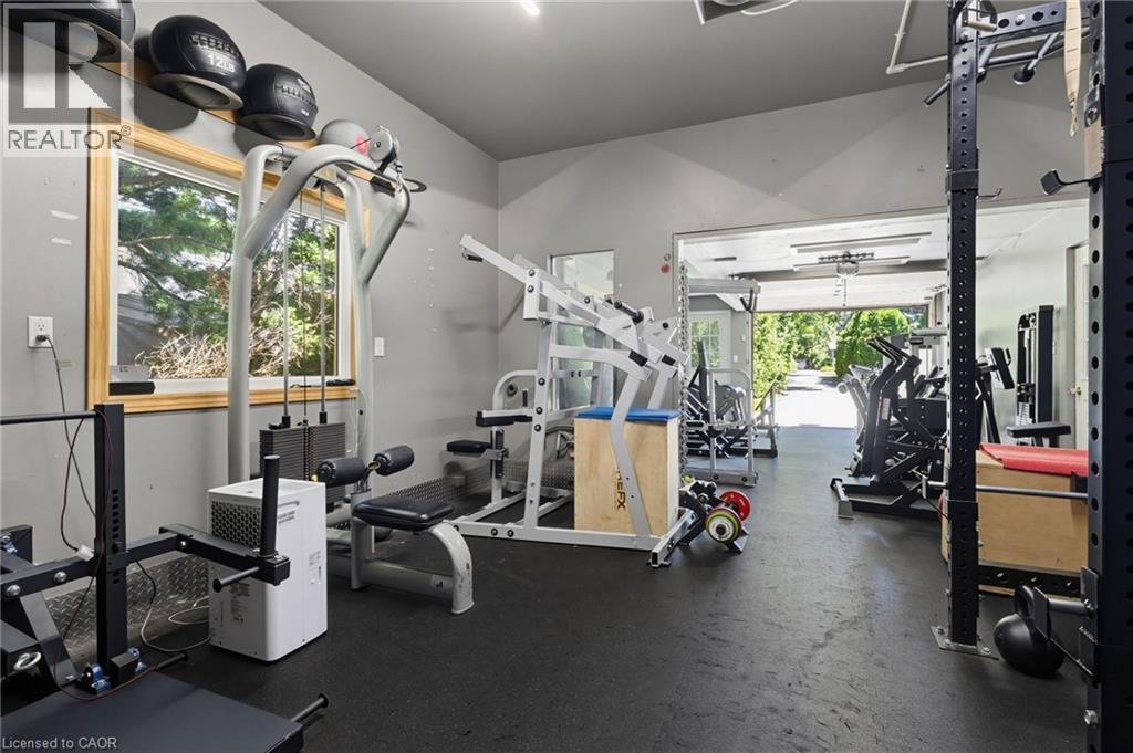 Dedicated fitness space featuring rubber flooring, a large window with natural wood trim, and a high ceiling - 21 Kerman Avenue, Grimsby, ON