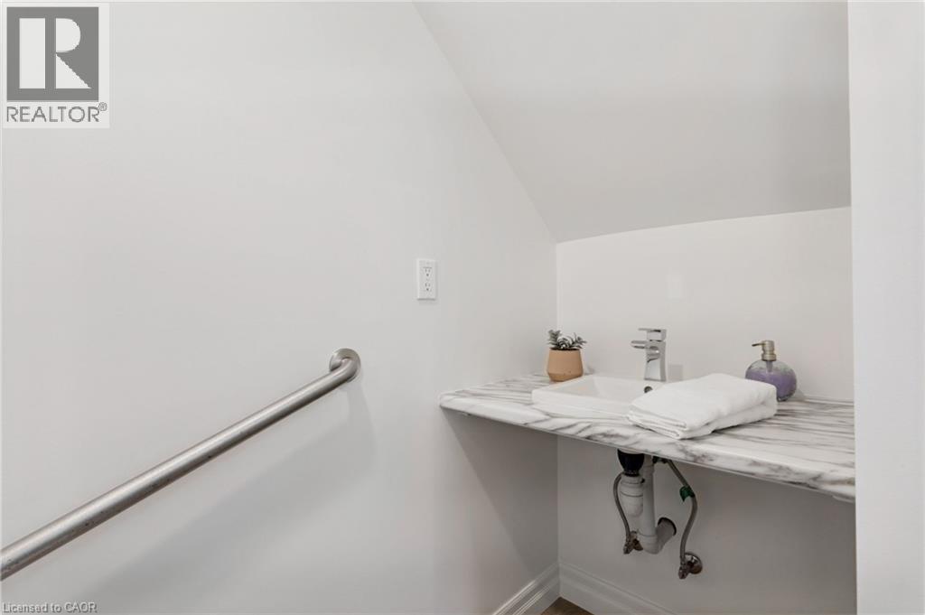 White wall paint, sloped ceiling, rectangular vessel sink, polished chrome faucet, and a patterned countertop - 21 Kerman Avenue, Grimsby, ON