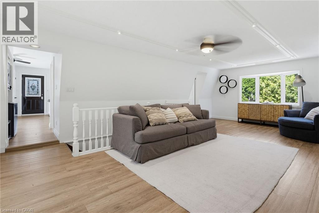 Wood-finish flooring throughout, white painted railing, bay window, ceiling fan, and recessed lighting - 21 Kerman Avenue, Grimsby, ON
