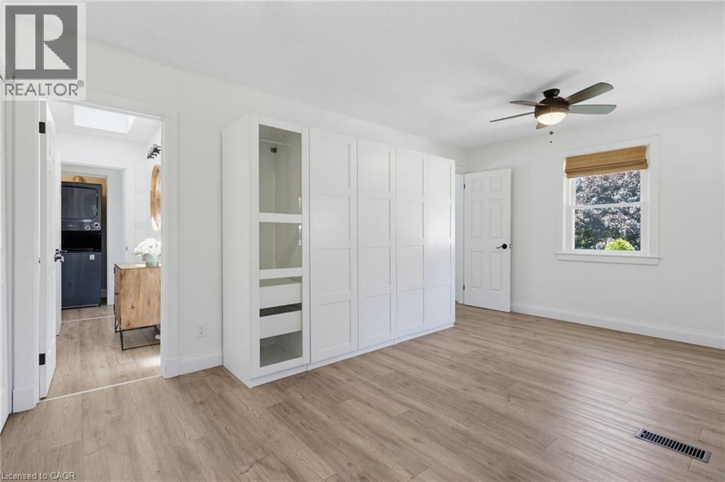 Wood-finish flooring, white built-in cabinetry with glass-front display, ceiling fan with integrated lighting, and a window with a woven shade - 21 Kerman Avenue, Grimsby, ON