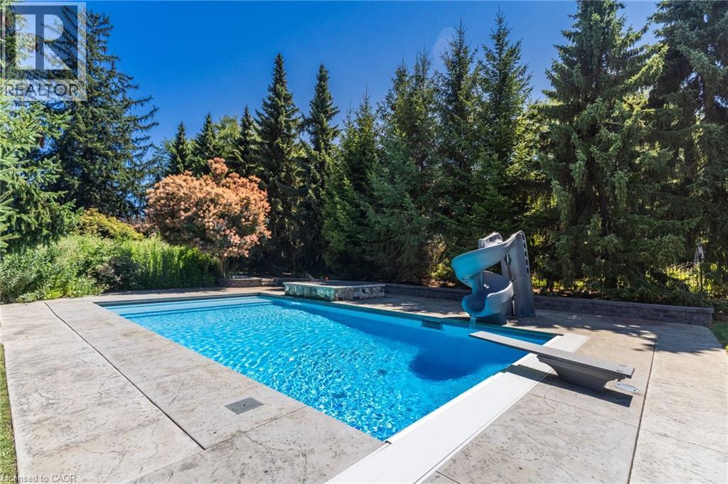 Rectangular swimming pool with a diving board and attached slide - 21 Kerman Avenue, Grimsby, ON