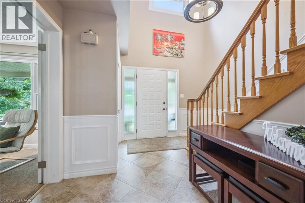 Tiled entryway featuring a decorative front door with frosted sidelights, a wood staircase, and wainscoting - 119 Sandy Ridge Place, Waterloo, ON - Indoor Photo Showing Other Room