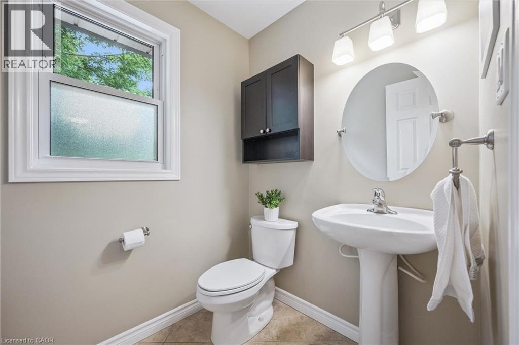 Pedestal sink with single-handle faucet, round wall mirror, track lighting fixture, and a built-in wall cabinet with shelving - 119 Sandy Ridge Place, Waterloo, ON - Indoor Photo Showing Bathroom