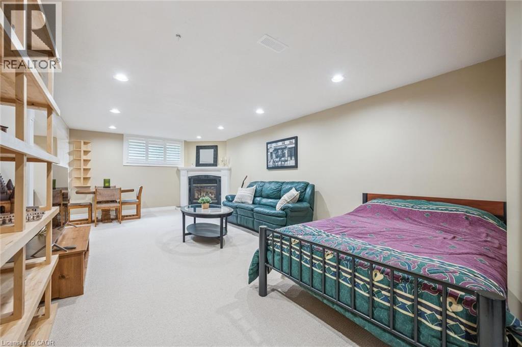 Recessed lighting, white window shutters, a white fireplace with a dark insert, light-toned carpeting, and a built-in wooden shelving unit - 119 Sandy Ridge Place, Waterloo, ON - Indoor