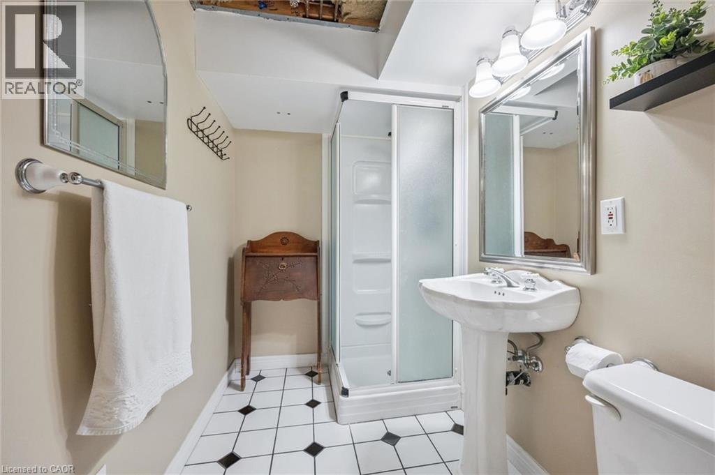 Compact bathroom featuring a shower enclosure, pedestal sink, and black and white flooring - 119 Sandy Ridge Place, Waterloo, ON - Indoor Photo Showing Bathroom