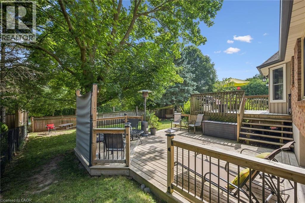 Multi-level wood deck with wood railings, brick exterior, bay window, and manicured lawn - 119 Sandy Ridge Place, Waterloo, ON - Outdoor With Deck Patio Veranda