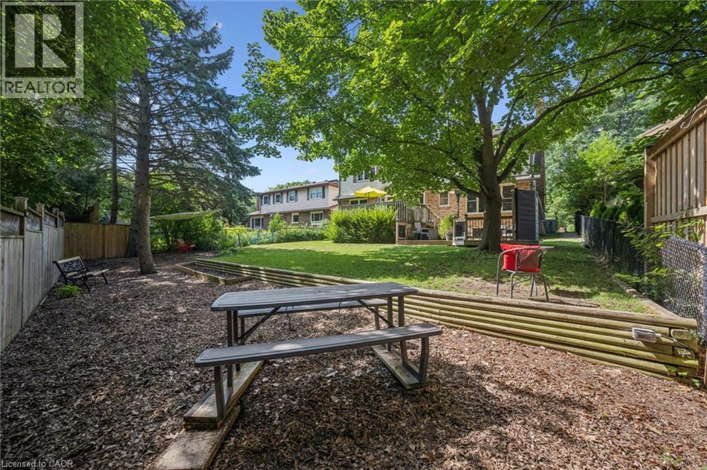 Expansive backyard featuring a manicured lawn, established trees, and wood fencing - 119 Sandy Ridge Place, Waterloo, ON - Outdoor With Deck Patio Veranda